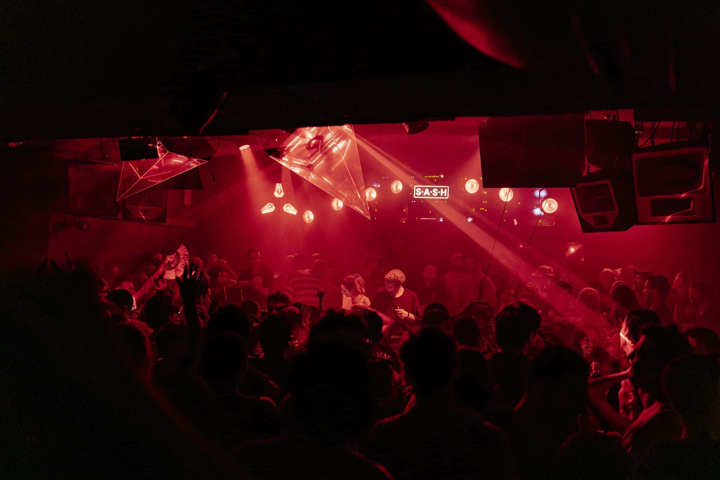 Red-lit S.A.S.H dancefloor with the logo above the crowd